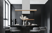 Modern kitchen with black cabinetry, marble island, and gray chairs.