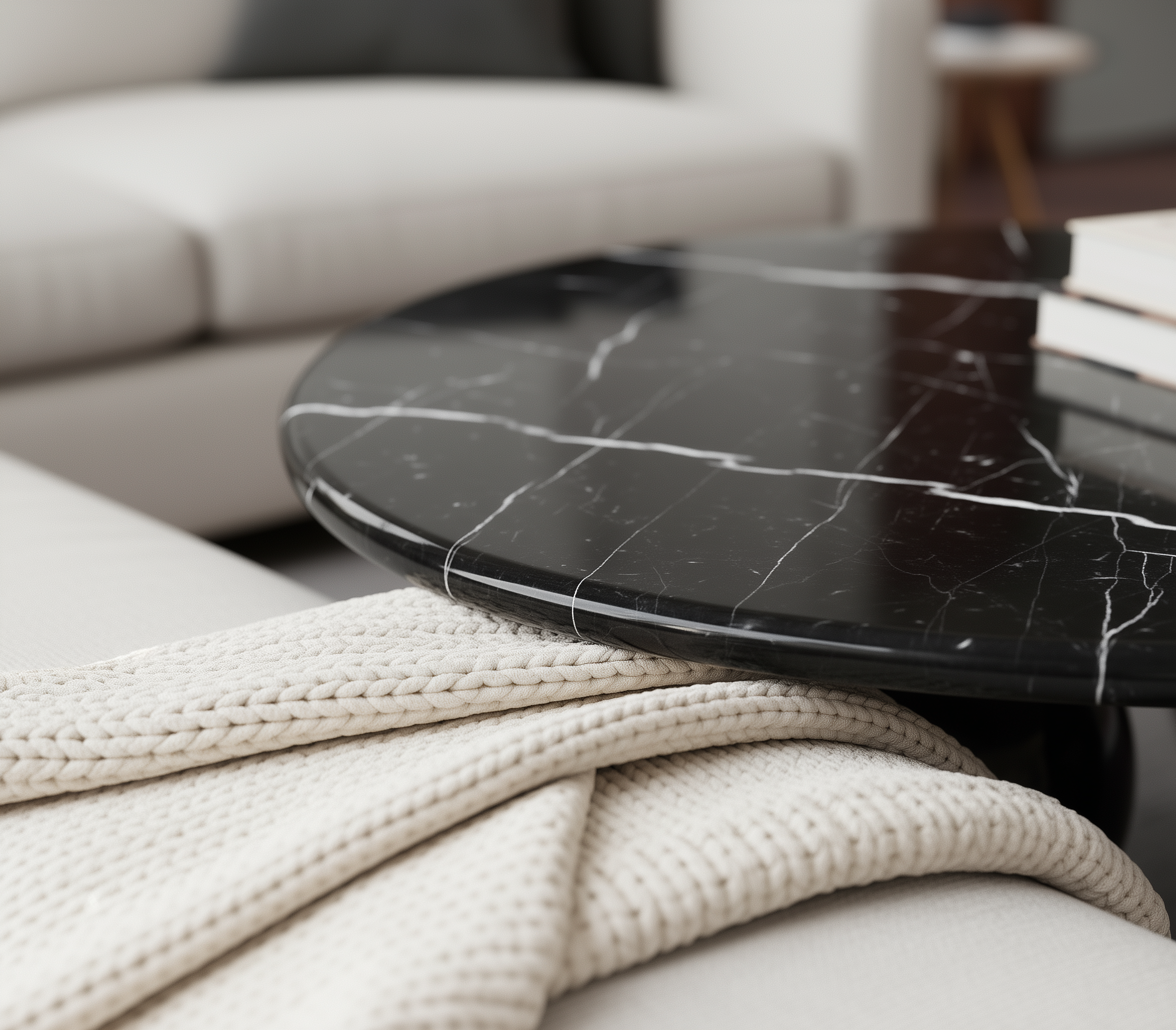Round black marble coffee table with a white textured blanket on a sofa in a living room setting.