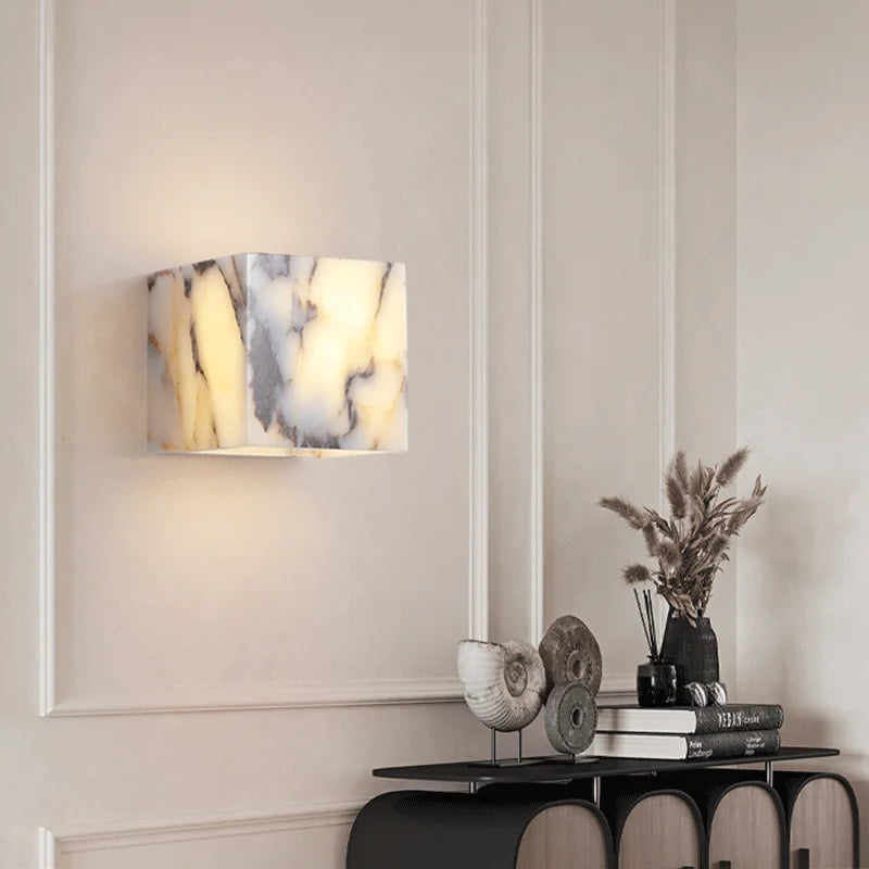 Decorative wall light fixture on a wall with a small table and decorative items below.