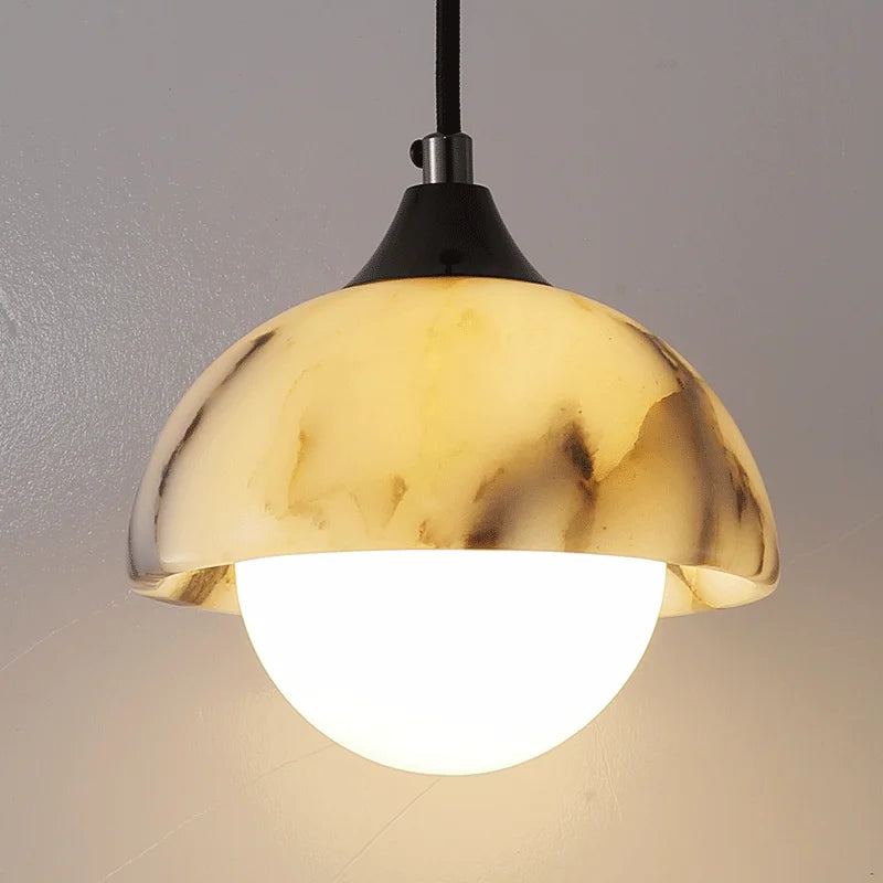 Gold pendant light with a white bulb on a neutral background