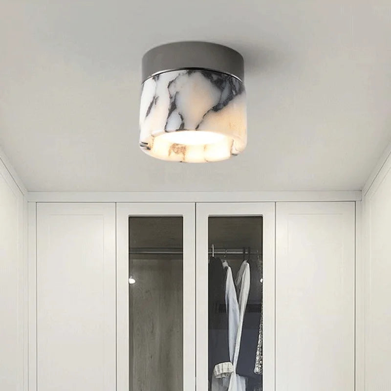 Ceiling light fixture with marble pattern in a room with white walls and a wardrobe.