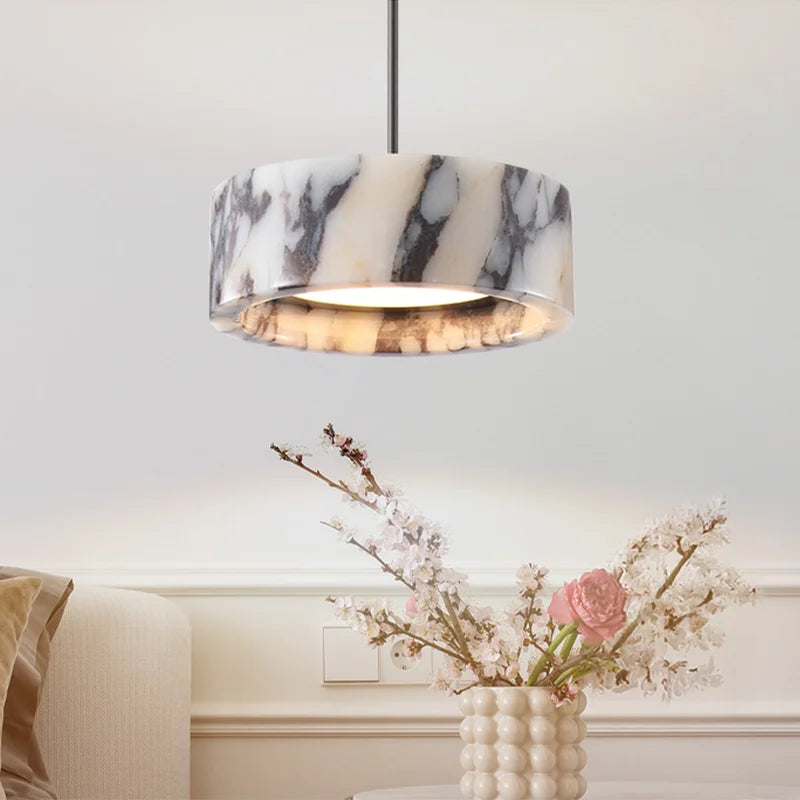 Marble-patterned pendant light fixture in a room with a vase of flowers on a table.