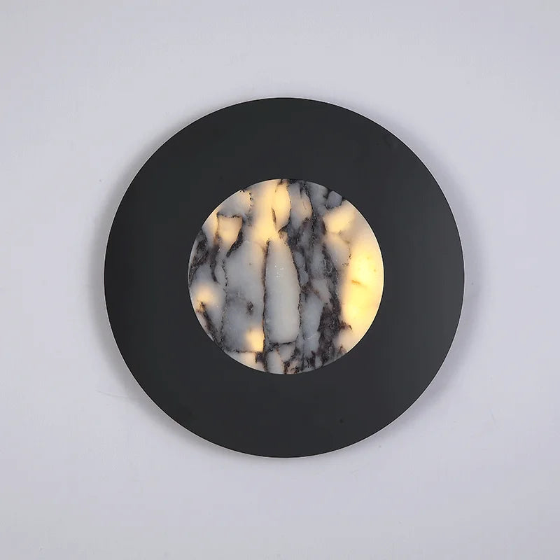 Round wall light fixture with black outer casing and marble-patterned inner circle on a light gray background