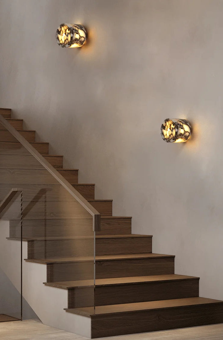Staircase with wall-mounted lights on a neutral wall.