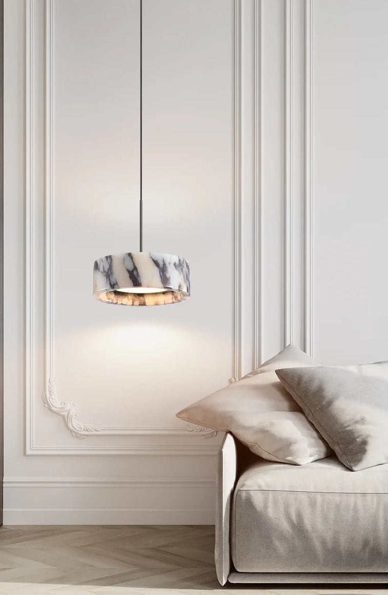 Modern interior with a light fixture and a sofa against a white paneled wall.