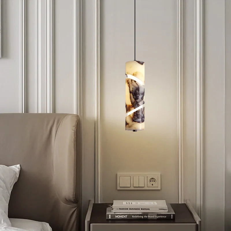 Modern pendant light fixture in a bedroom setting with a bed and nightstand.
