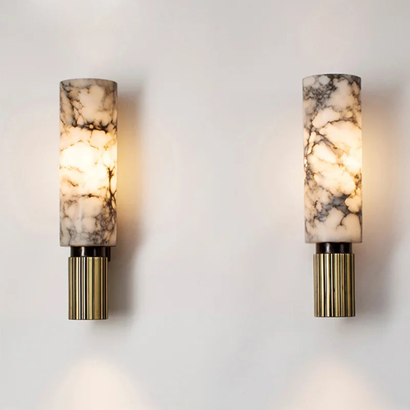 Two wall sconces with marble-like lampshades and brass bases on a light gray wall.