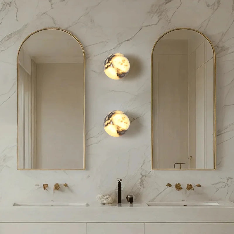 Bathroom with two arched mirrors, wall lights, and a sink.