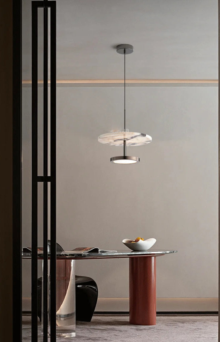 Modern pendant light hanging above a dining table in a minimalistic interior setting.