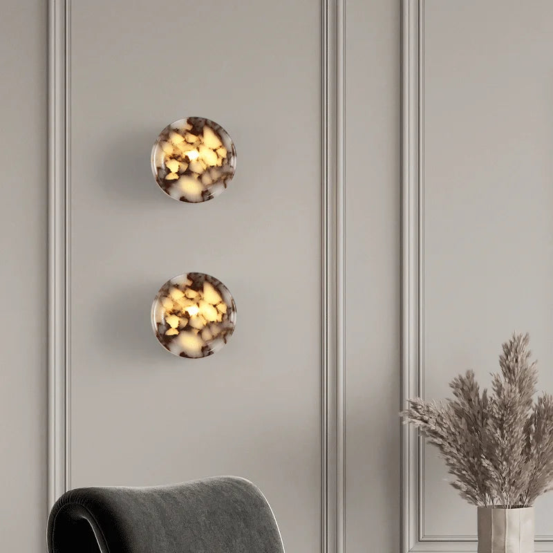 Decorative wall lights with a neutral background and a plant on the right.