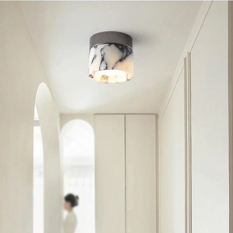 Ceiling light fixture with marble pattern in a room with white walls and a door.