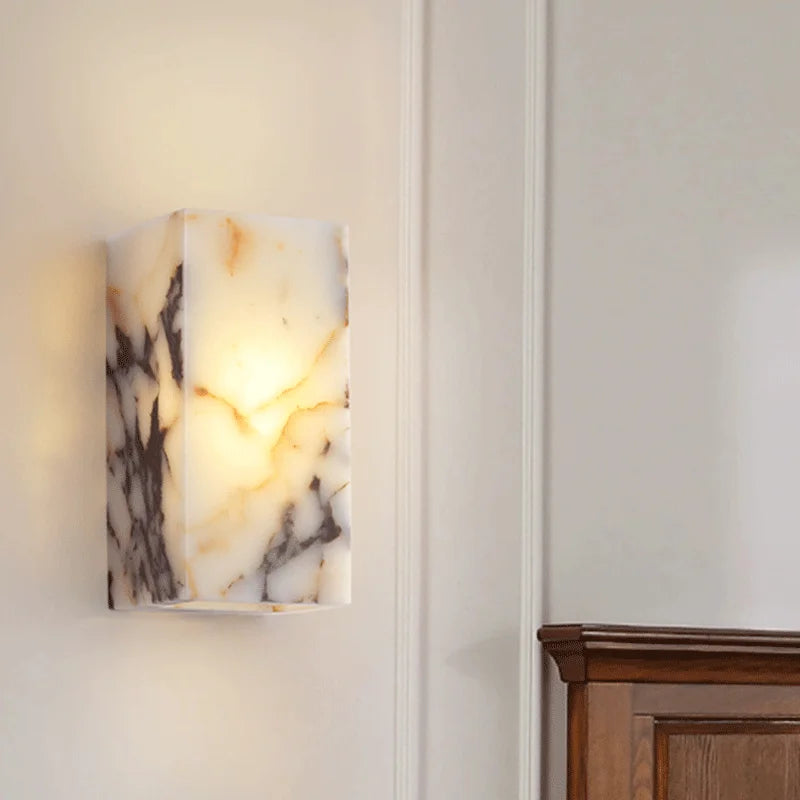 Marble-patterned wall sconce on a neutral wall with wooden furniture.