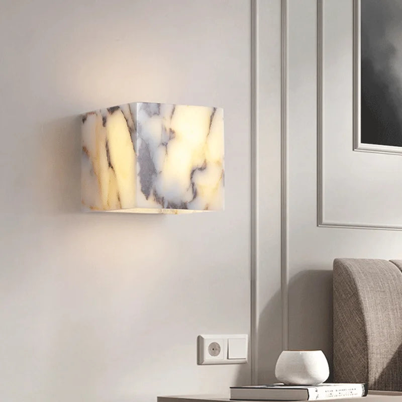 Marble-patterned wall light fixture on a white wall with a sofa and books in the background.