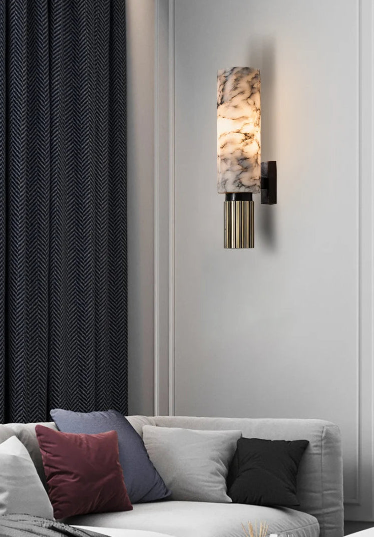 Wall-mounted lamp with marble-like design on a gray wall above a sofa with colorful cushions.
