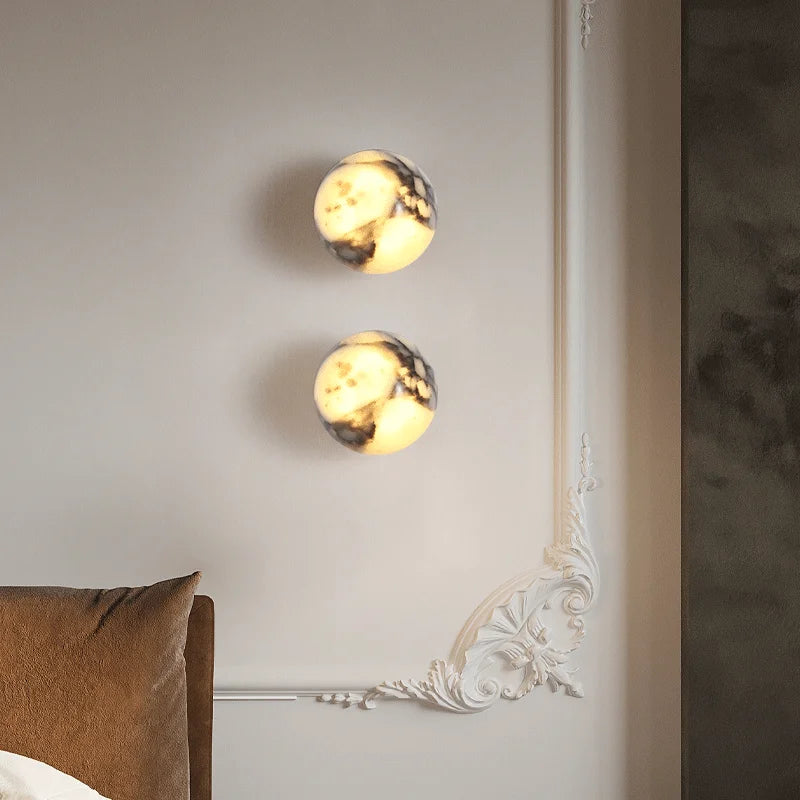 Two spherical wall lights on a neutral wall with decorative elements.