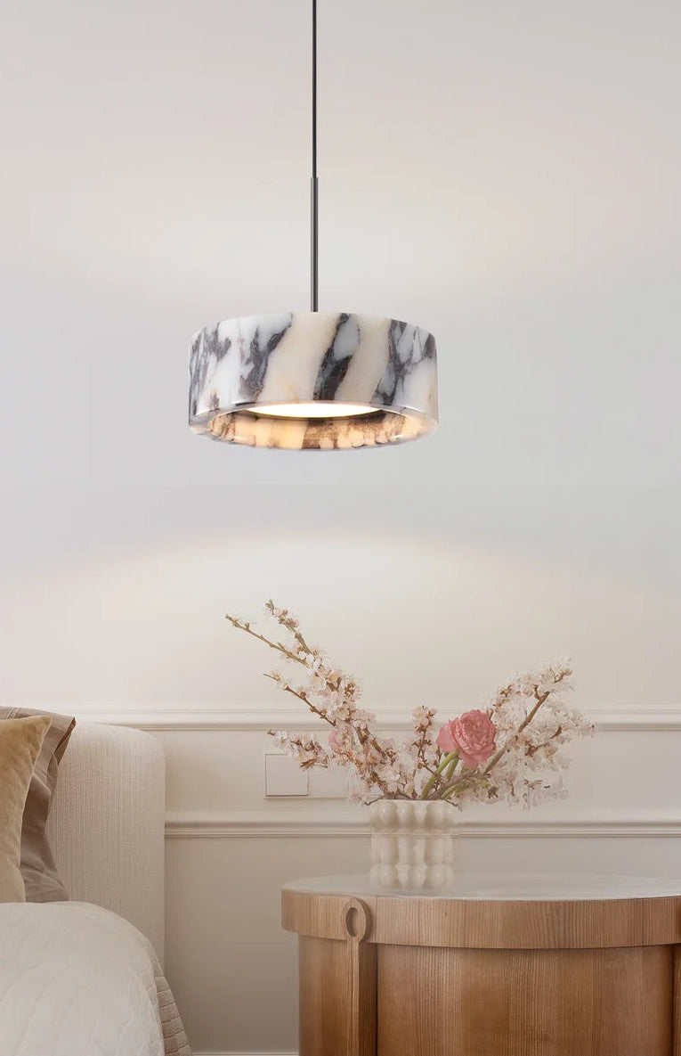 Marble-patterned pendant light hanging above a wooden side table with decorative flowers.