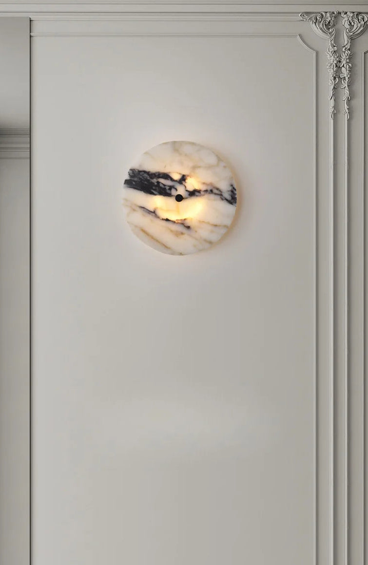 Round wall sconce with marble-like finish on a light gray wall.
