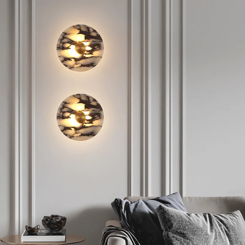 Two round wall lights on a gray wall with a sofa and decorative items below.