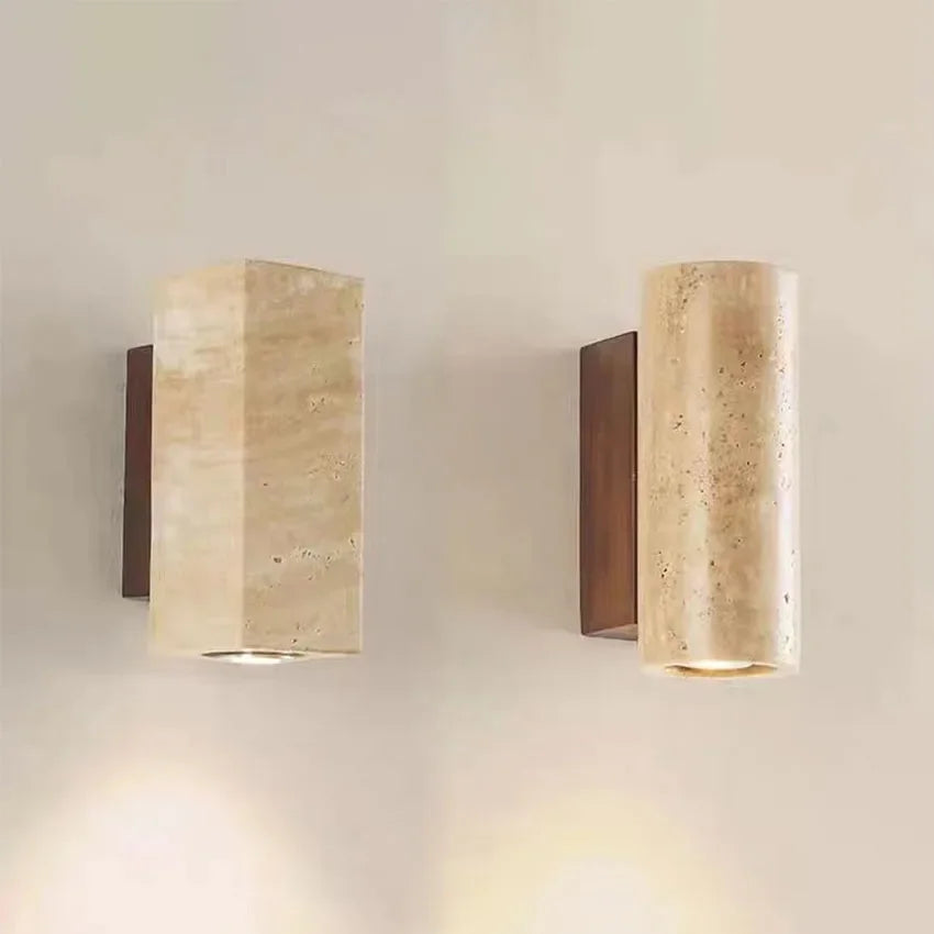 Two cylindrical wall lights with beige stone-like finish and bronze base on a neutral wall.