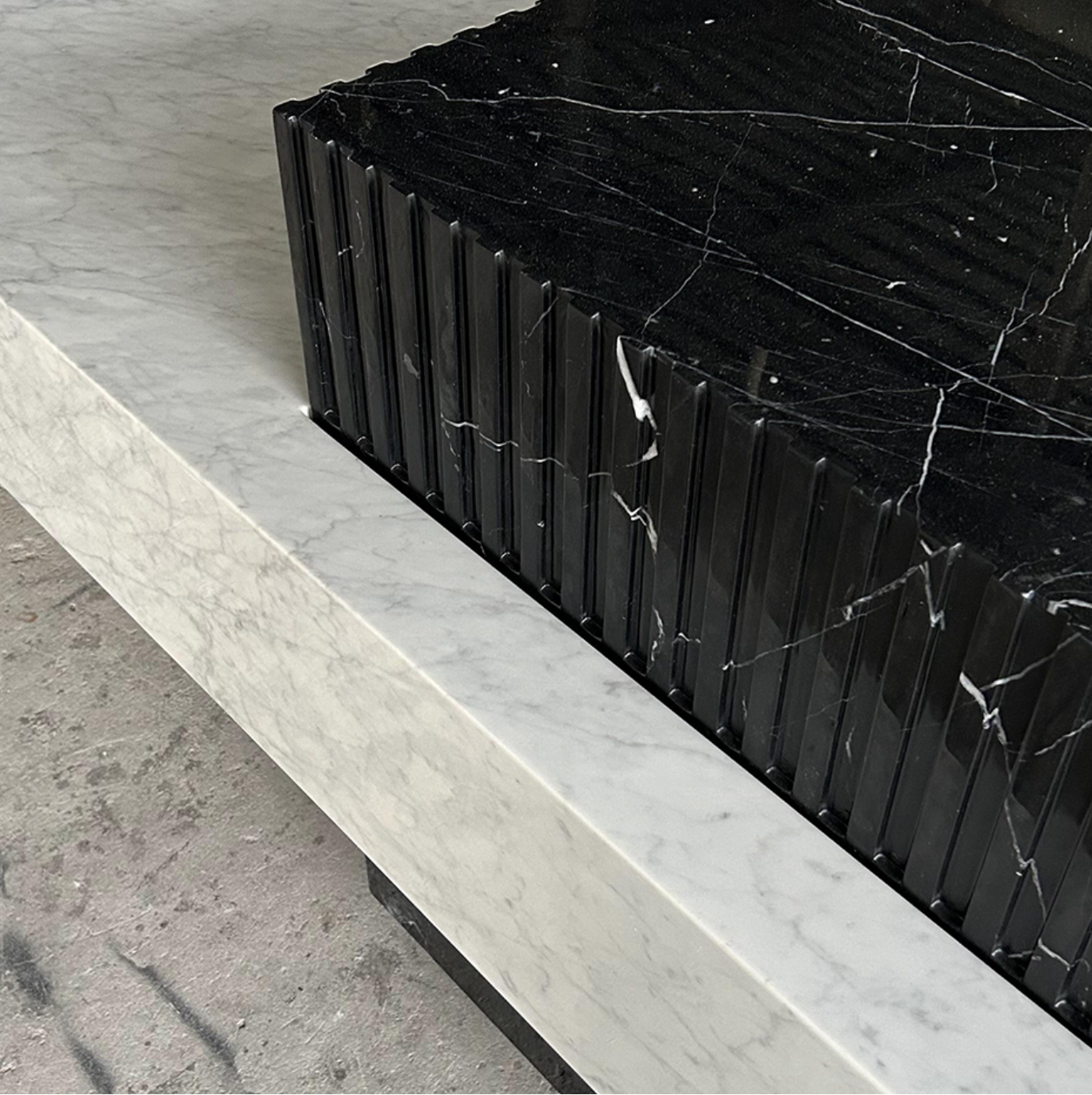 Close up of Carrara and Nero Marquina marble kitchen island with dual stone contrast design