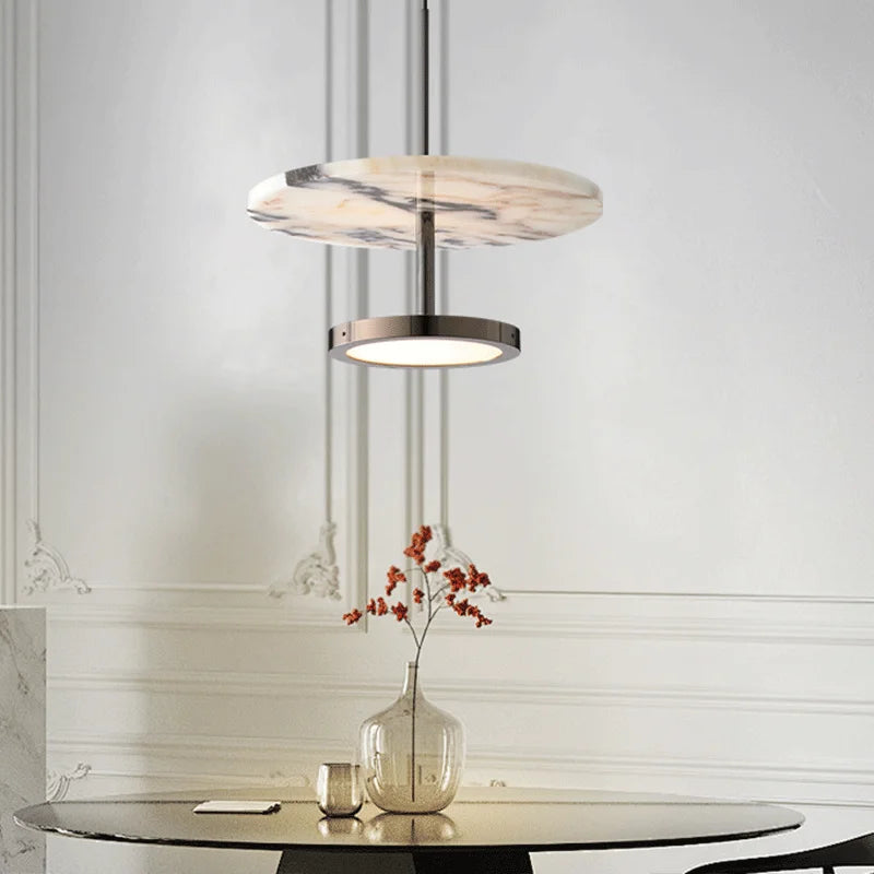 Modern pendant light fixture hanging above a round table with decorative elements.