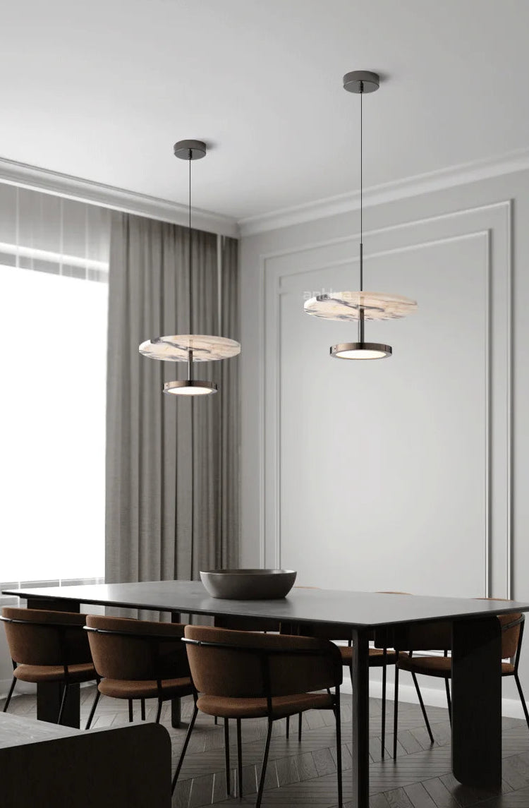 Modern dining room with a long table and chairs, featuring pendant lights.