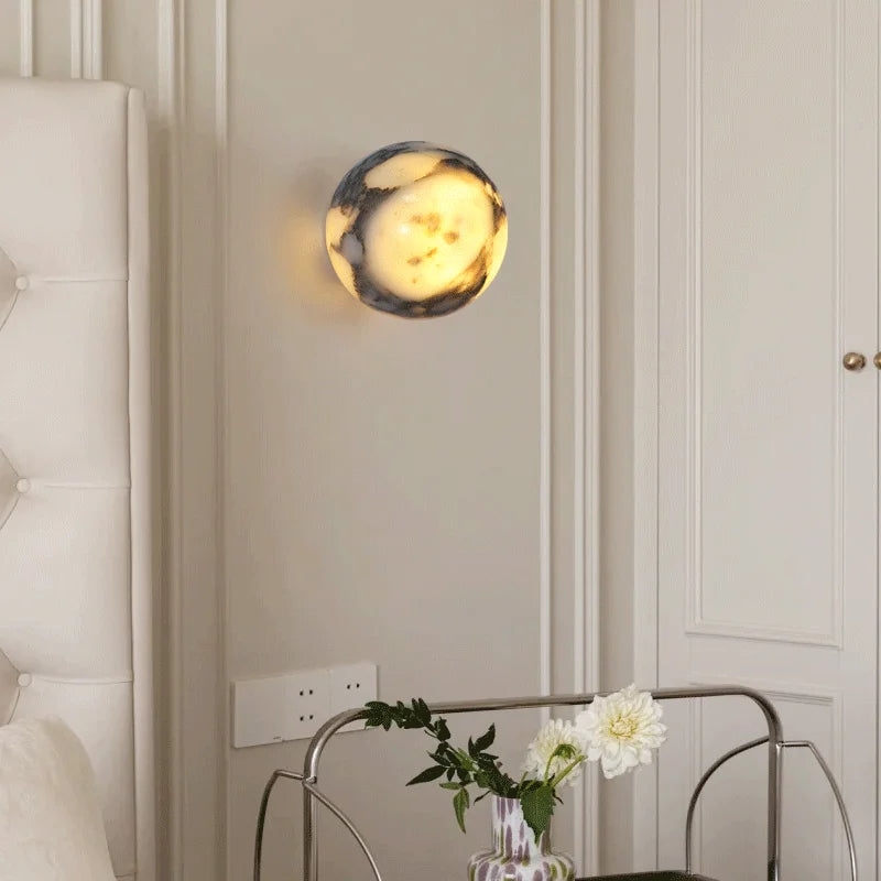 Decorative wall sconce on a wall with a table and flowers in the foreground