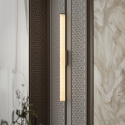 Wall-mounted light fixture with decorative metal grille on a textured wall.