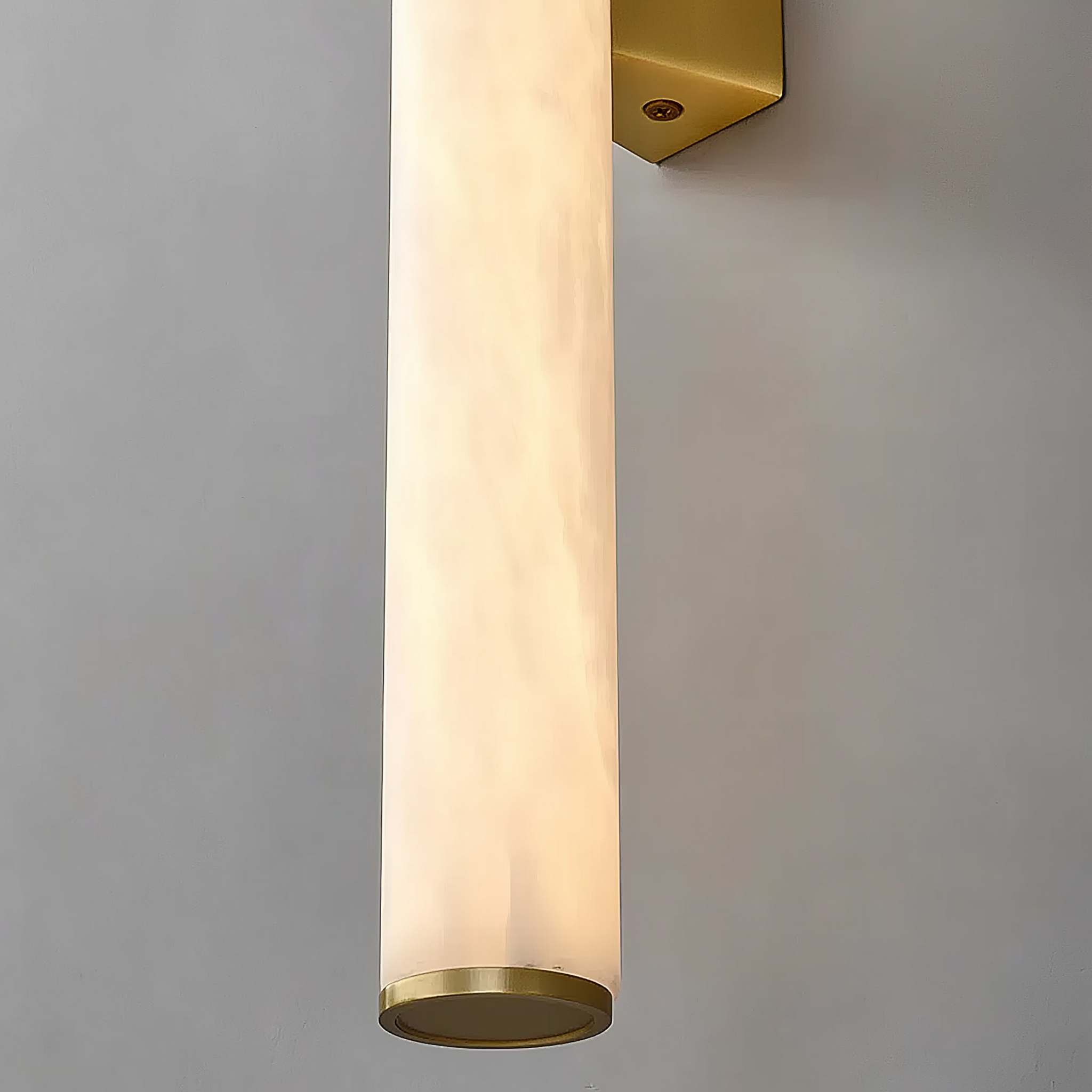 Cylindrical wall sconce with gold fixture on a gray background