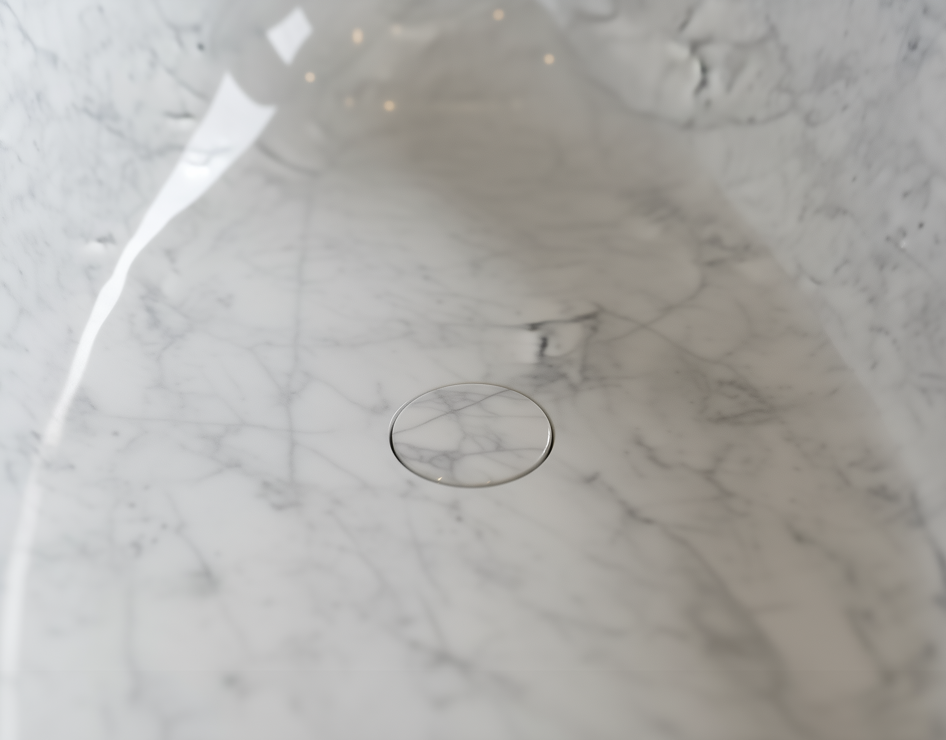 Close-up of a marble-patterned surface with a circular drain.